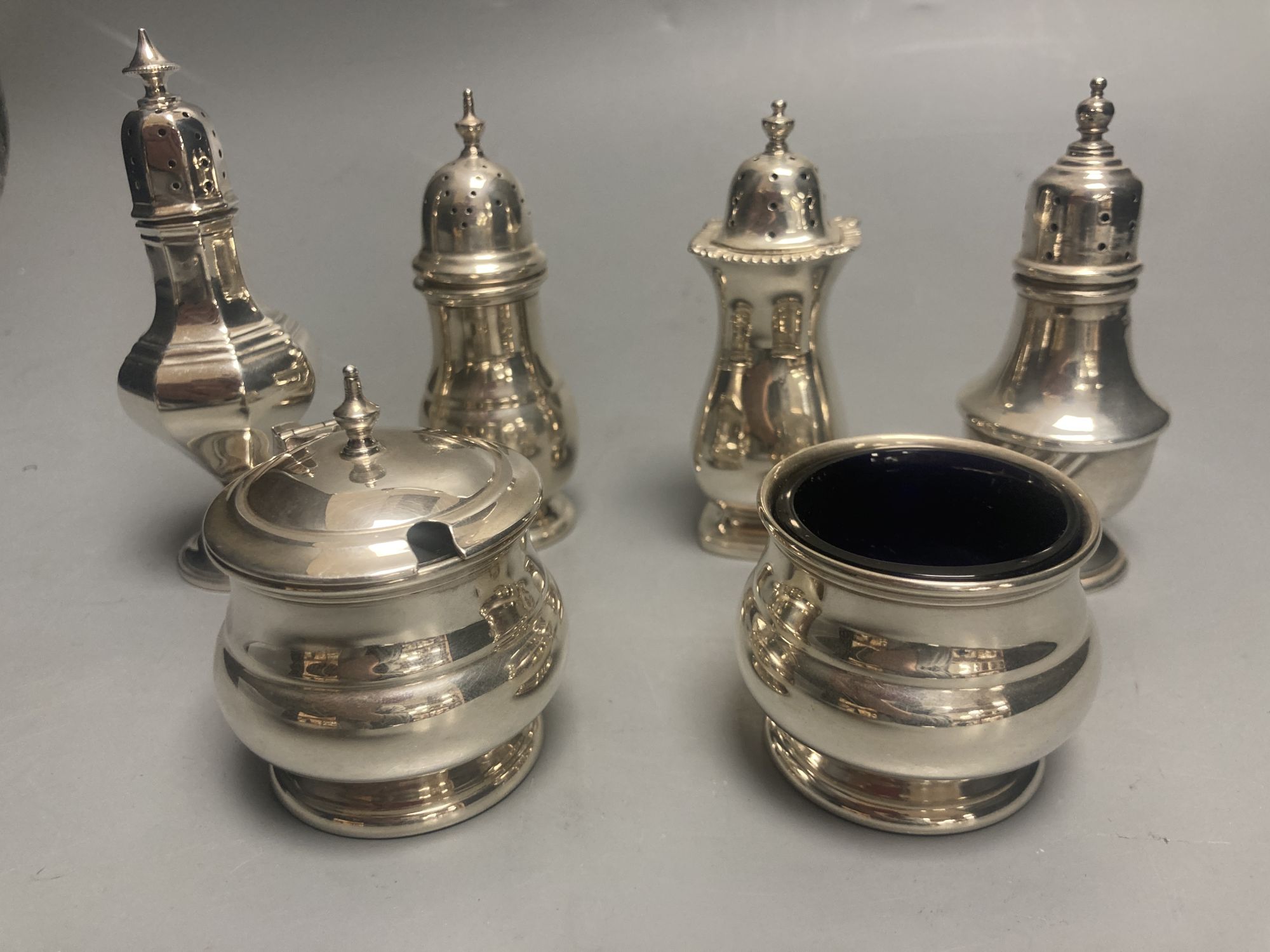 A George V three piece silver condiment set, Birmingham, 1935 and three other silver pepperettes, gross 7.5oz.